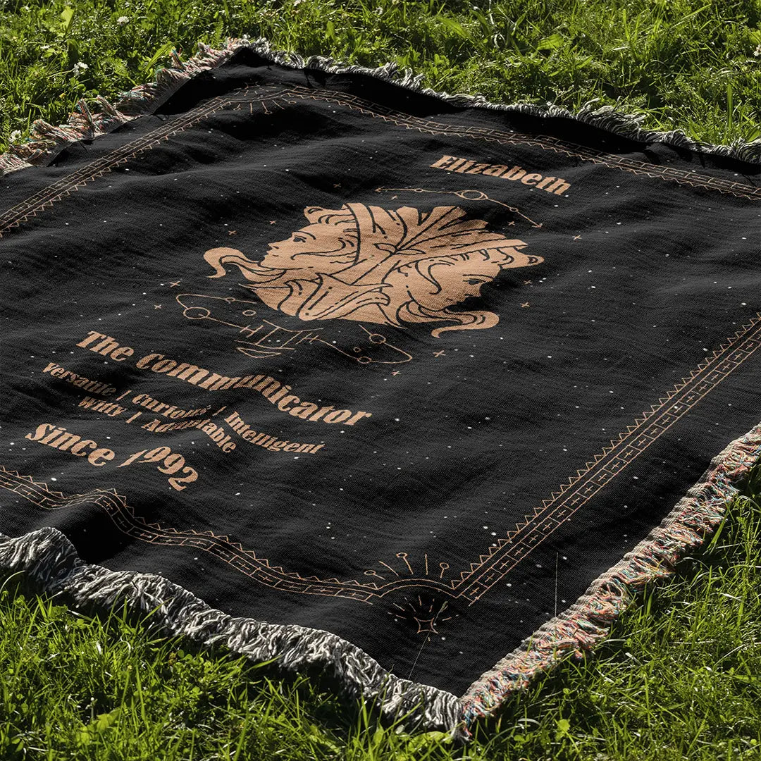 Custom woven cotton blanket with Gemini-themed elements laid flat on a sunlit grassy area.