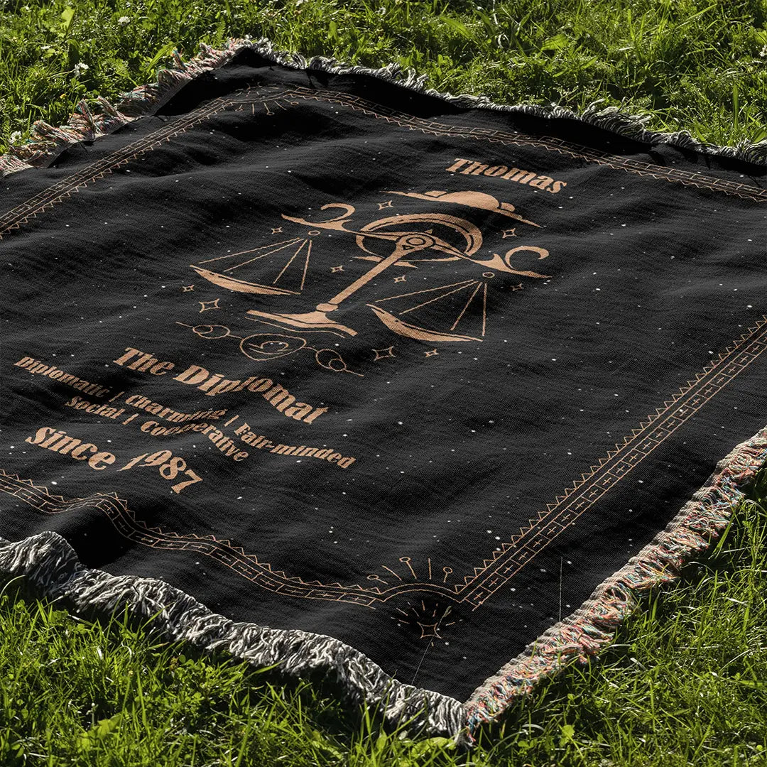 Libra zodiac custom woven cotton blanket laid out on green grass in a sunny outdoor setting.