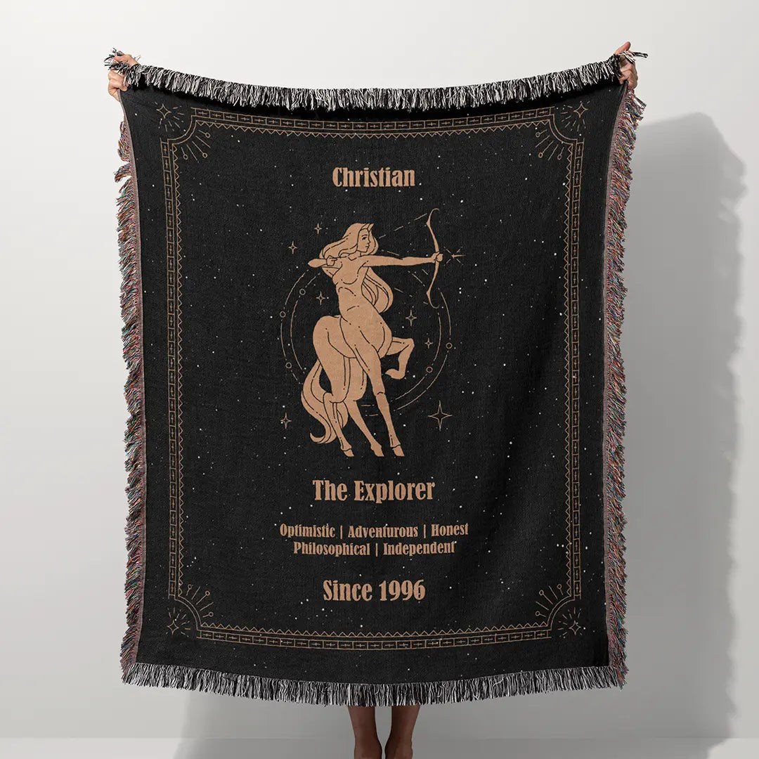 A custom blanket featuring a Sagittarius zodiac design held up on a white background, showcasing a personalized name, date, and traits.