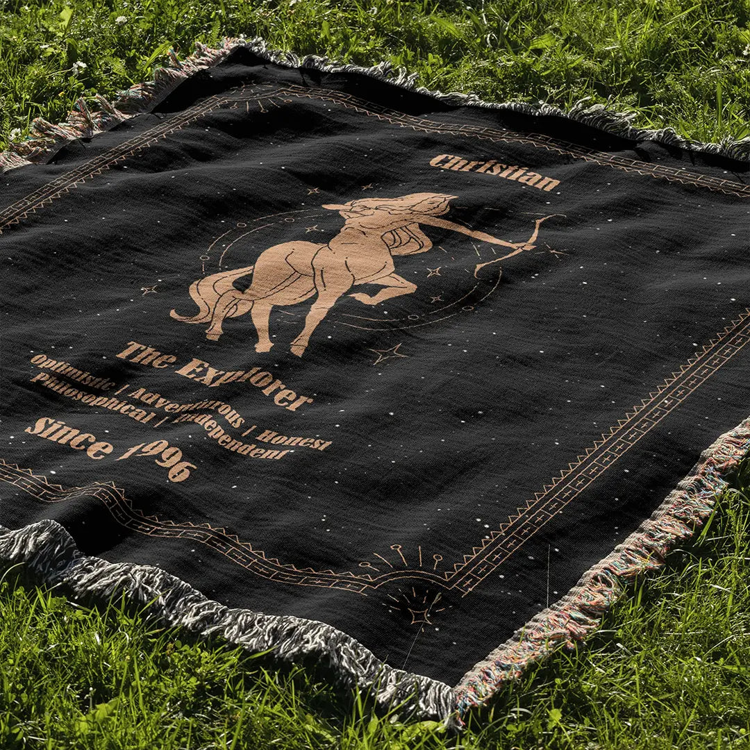 A Sagittarius design custom woven cotton blanket spread across lush grass, showing the detailed centaur archer artwork under natural daylight.
