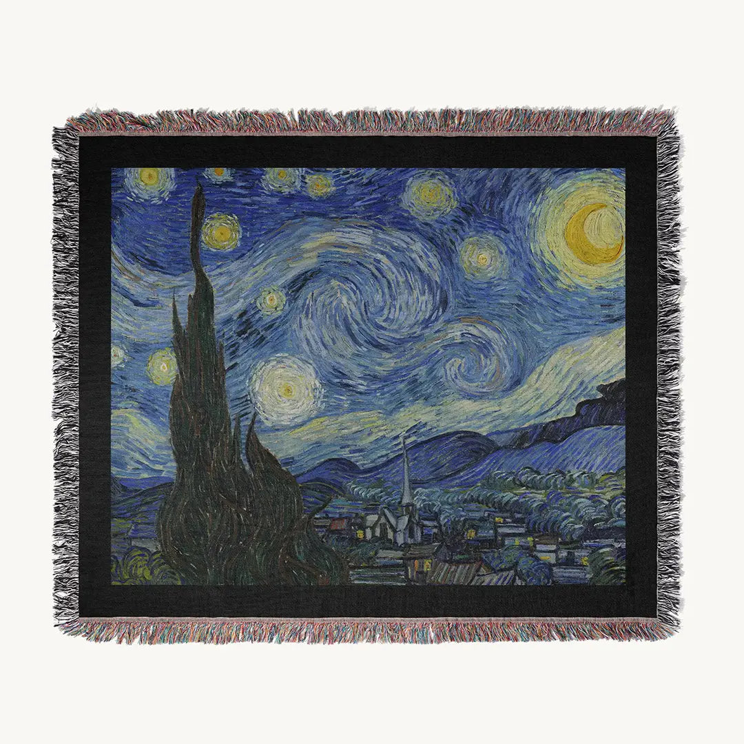 Flat-lay of "The Starry Night" woven cotton blanket on white background, displaying the entire van Gogh artwork bordered in black with multicolor fringe.