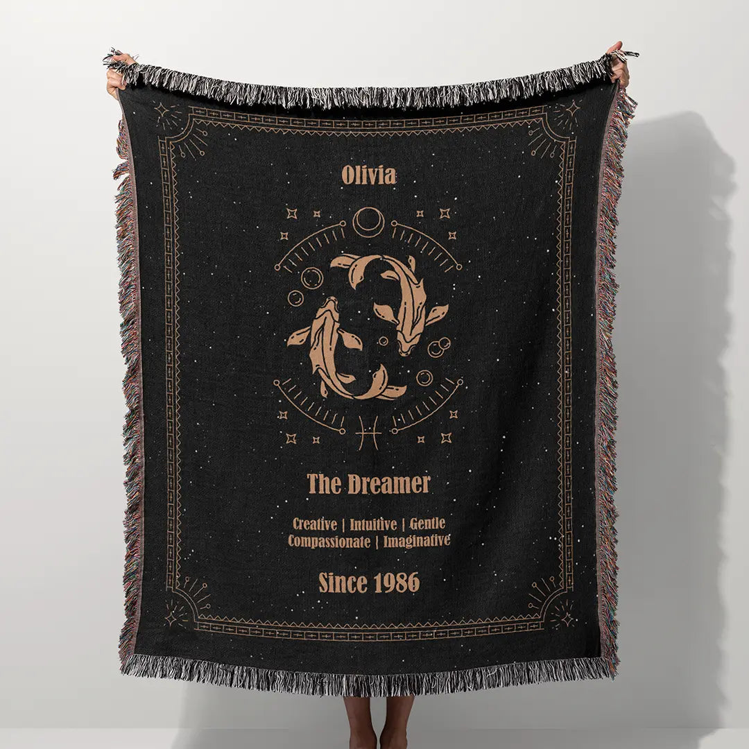 A custom blanket featuring a Pisces zodiac design held up on a white background, showcasing a personalized name, date, and traits.
