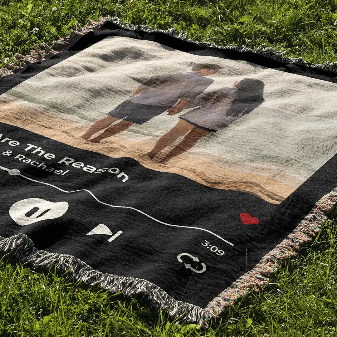 Personalized music player woven cotton blanket for couples, laid flat on green grass, showing its full design and fringed edges.