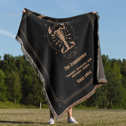 Man holding up a custom woven cotton blanket featuring a Scorpio zodiac design with a custom name and traits, set against a forest background.