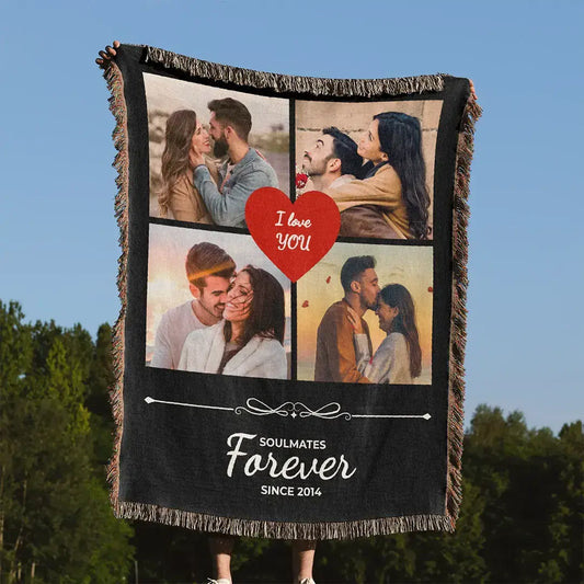 Personalized black woven photo cotton blanket for couples with fringed edges held outdoors against a blue sky and green trees.