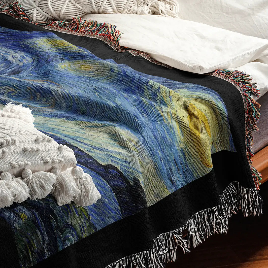 Close-up of "The Starry Night" woven cotton blanket draped on a bed, showcasing the detailed texture of the iconic swirling night sky artwork by Vincent van Gogh.