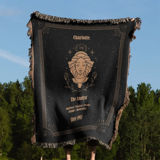 A custom woven cotton blanket featuring a Virgo zodiac design held up outdoors with a forest in the background, showcasing a custom name and traits.