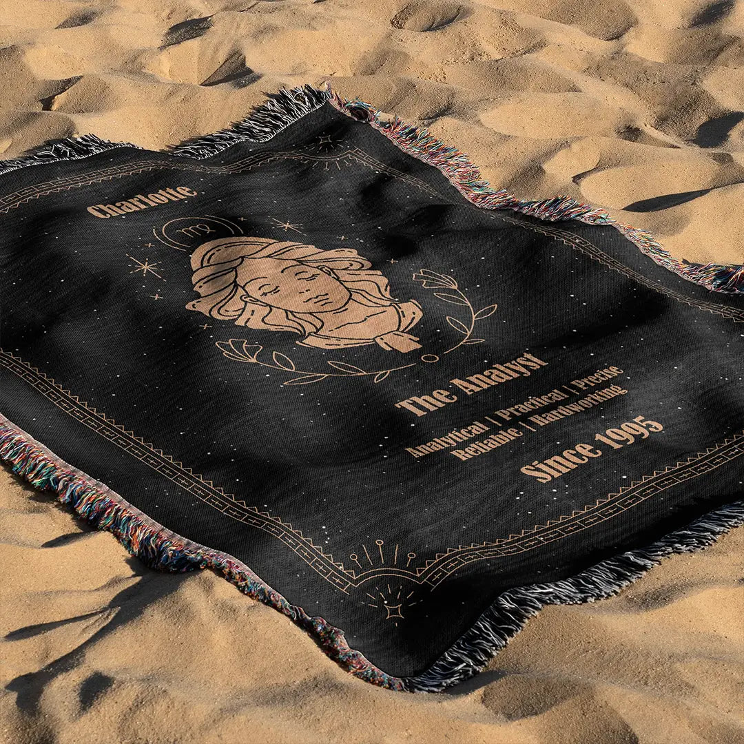 Custom woven cotton blanket with Virgo zodiac design laid out on the sand, highlighting the detailed illustration and a custom name.